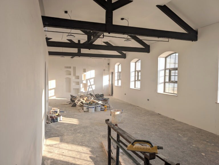 The studio mid-build, with building materials on the floor and the niche wall taking shape at the far end