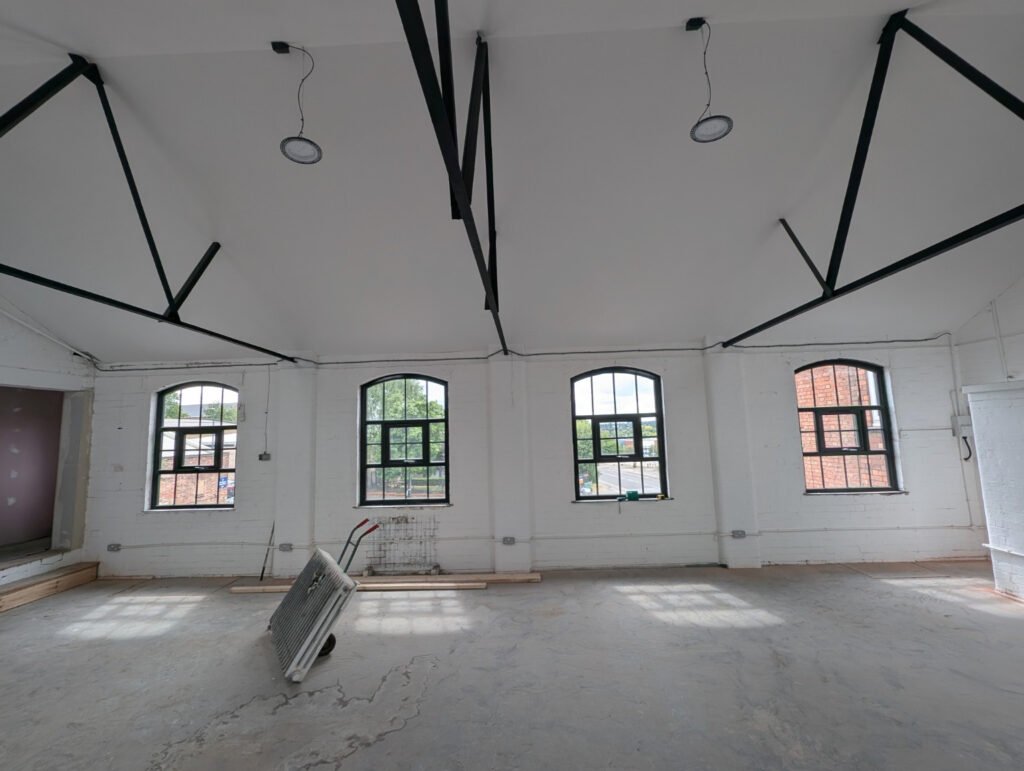The empty studio space before the build, with four arched windows and a bare concrete floor