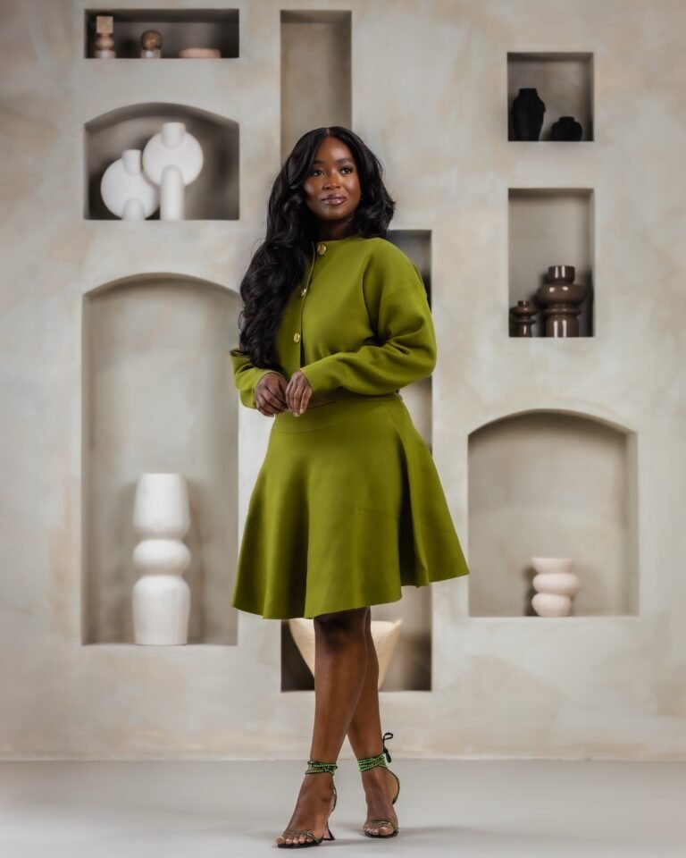 Jariatu in a green knit set in front of the finished Sanctuary niche wall