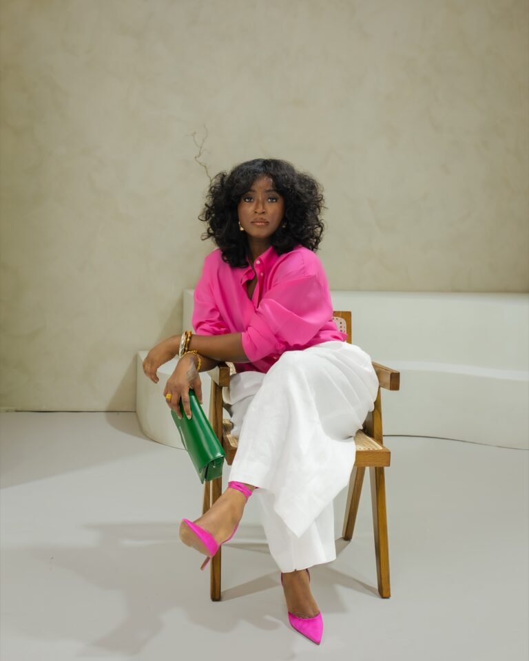 Jariatu seated in a pink shirt and white trousers in the finished Sanctuary